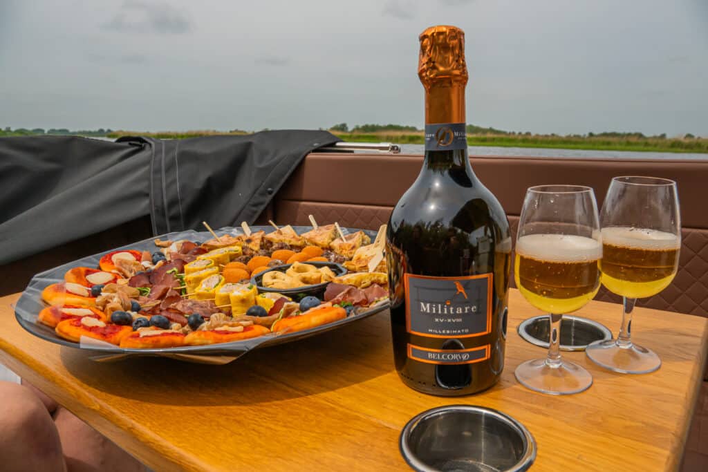 Luxe borrelplank met diverse hapjes en bubbels aan boord van een sloep op de Friese Meren.